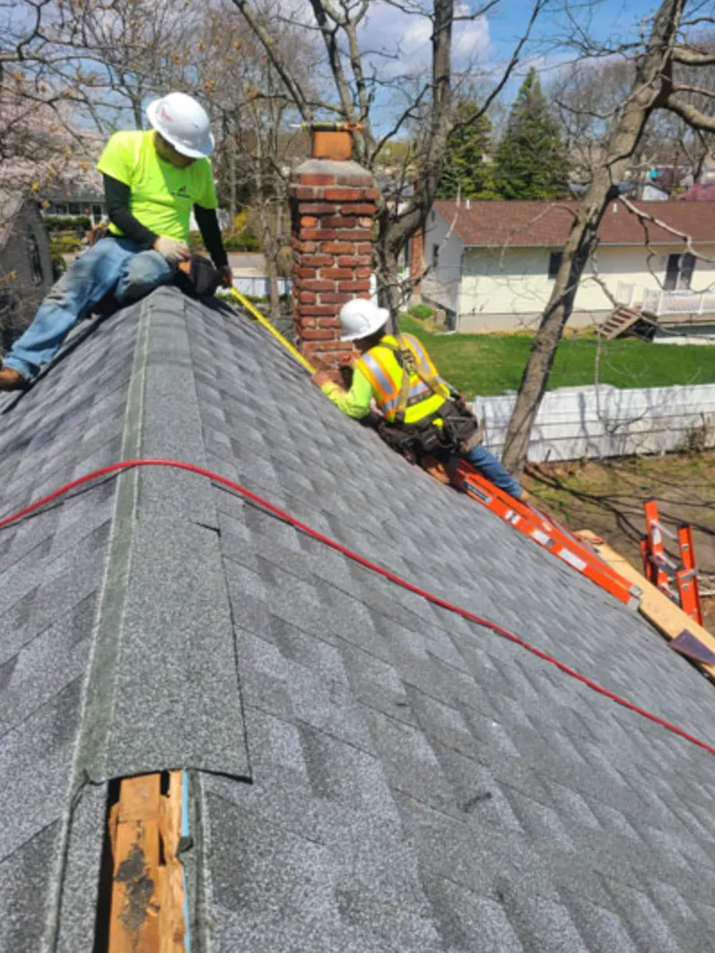 Roofers in hard hats installing asphalt shingles