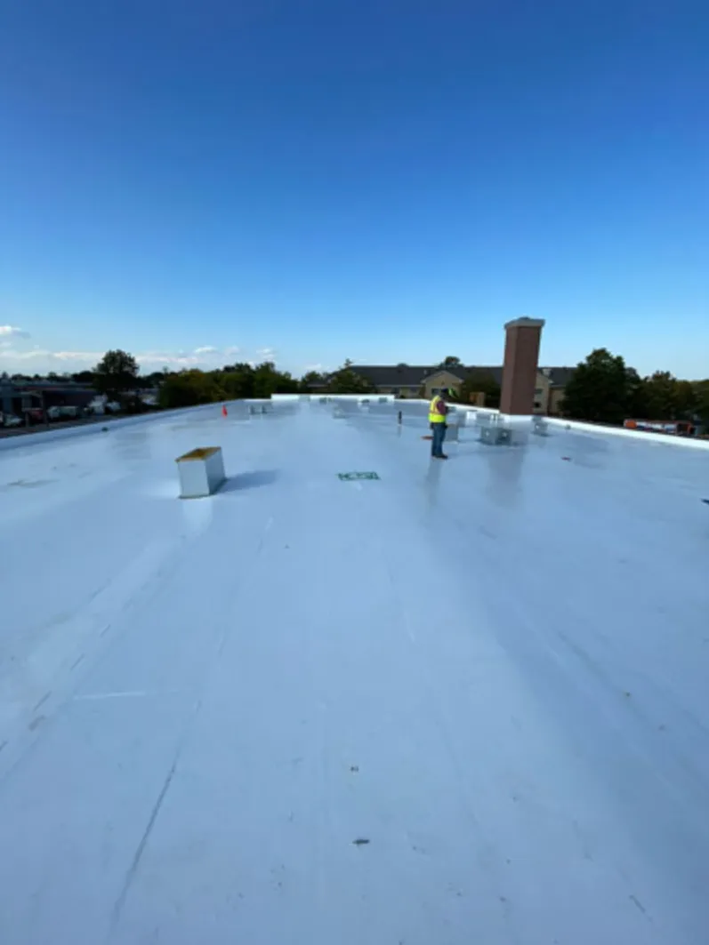 Large white commercial flat roof membrane with crew member inspecting