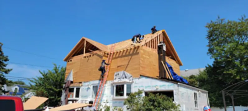 Crew sheathing a new full dormer on a house