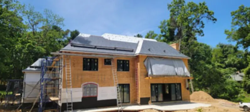 Large new custom home under construction with slate-style roof and scaffolding