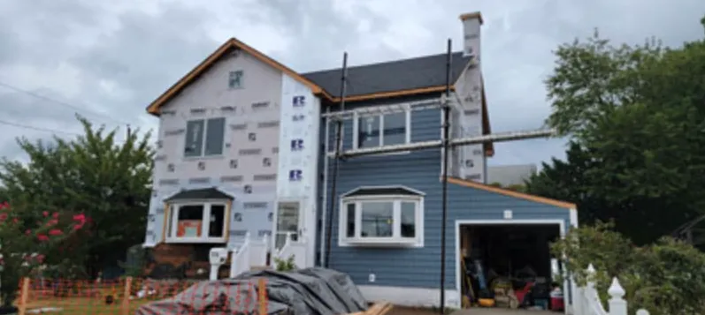 Colonial during a re-side, half in house wrap and half in new blue siding