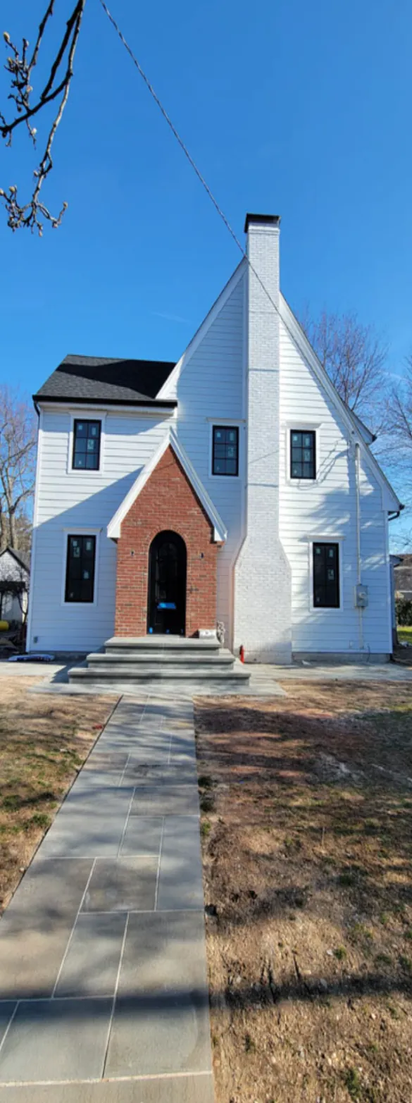 Finished white Tudor-style custom home with brick arched entry